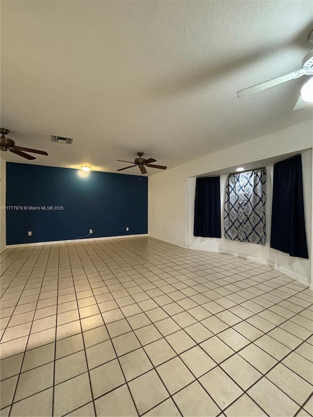 spare room with a ceiling fan, a textured ceiling, visible vents, and light tile patterned floors