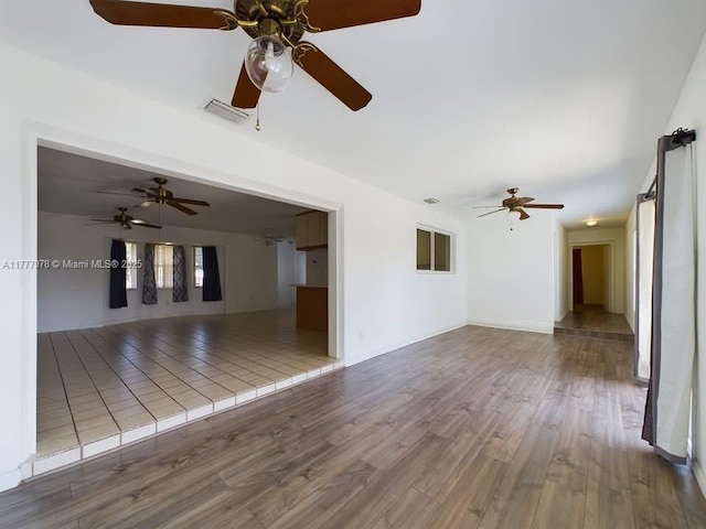 unfurnished living room featuring wood finished floors, visible vents, and a ceiling fan