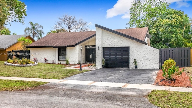 mid-century home with a front yard, a shingled roof, a garage, fence, and driveway