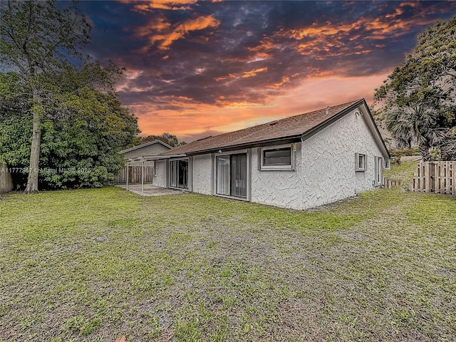 back of house with a yard, stucco siding, and a fenced backyard