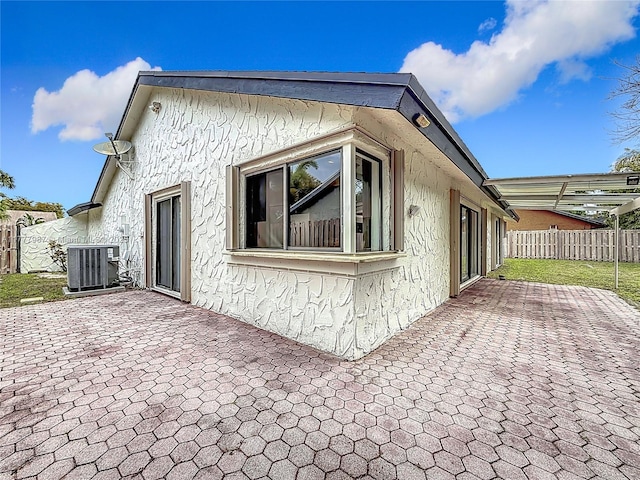 view of home's exterior featuring a patio, central AC, fence, and stucco siding