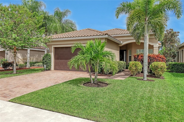 mediterranean / spanish house with a tiled roof, a garage, a front yard, stucco siding, and decorative driveway