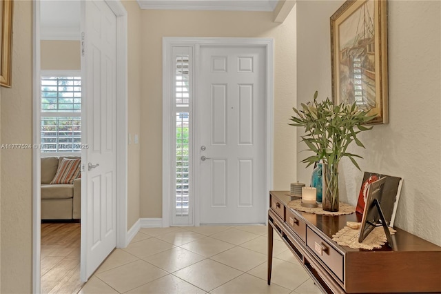 foyer featuring a textured wall, ornamental molding, and light tile patterned floors