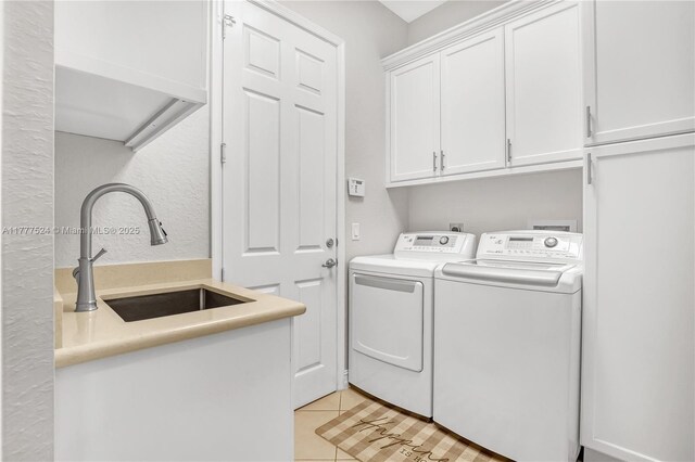 washroom featuring cabinet space, washing machine and clothes dryer, light tile patterned floors, and a sink