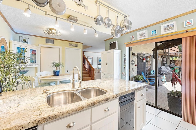 11861 SW 13th Ct, Davie, FL 33325 - kitchen with a sink, a textured ceiling, light tile patterned floors, white cabinets, and light stone countertops