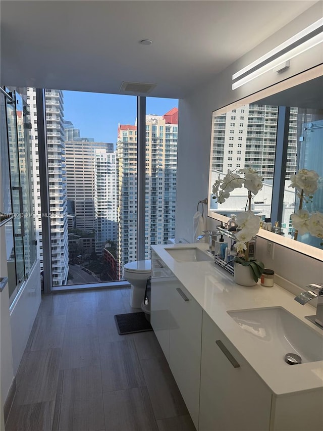 bathroom featuring toilet, a healthy amount of sunlight, a sink, and a stall shower
