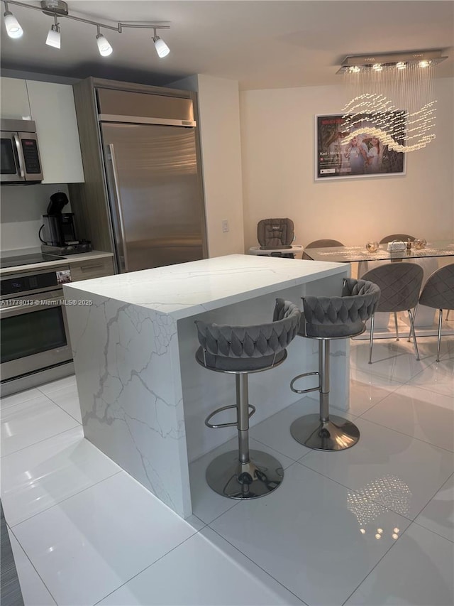 kitchen with light stone countertops, a breakfast bar area, a center island, stainless steel appliances, and modern cabinets