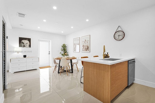 kitchen featuring light countertops, a sink, a kitchen breakfast bar, visible vents, and recessed lighting