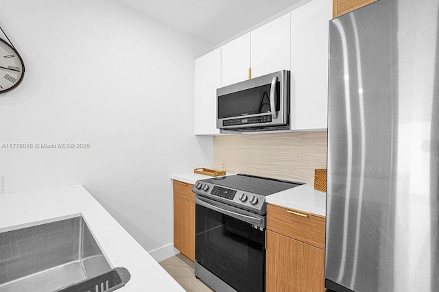 kitchen with white cabinetry, light countertops, appliances with stainless steel finishes, and backsplash