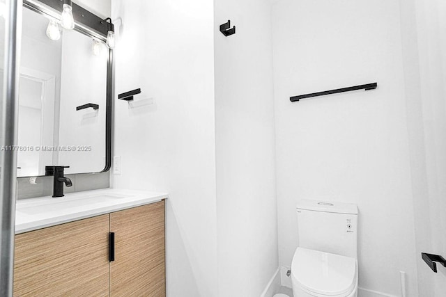 bathroom with toilet, vanity, and baseboards