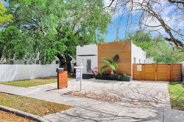 view of front of house featuring stucco siding, a gate, and fence