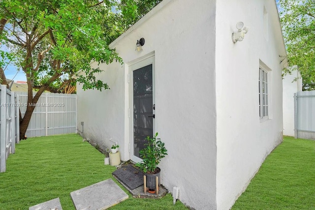 exterior space with stucco siding, fence, and a lawn