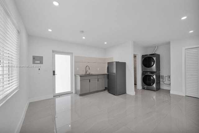 kitchen with stacked washer / drying machine, recessed lighting, a sink, gray cabinetry, and freestanding refrigerator