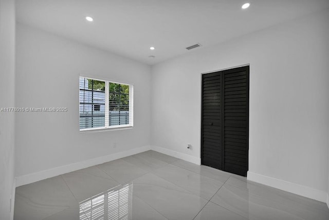 empty room featuring baseboards, visible vents, and recessed lighting