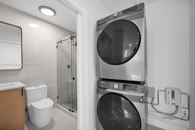 laundry area featuring stacked washer and clothes dryer, laundry area, and tile walls
