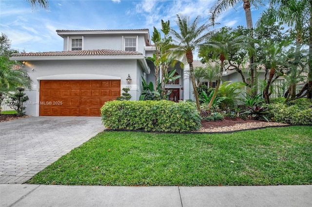 view of front of home with a garage, a tile roof, stucco siding, a front lawn, and decorative driveway