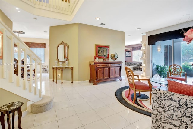 hall featuring a healthy amount of sunlight, light tile patterned floors, baseboards, and stairway