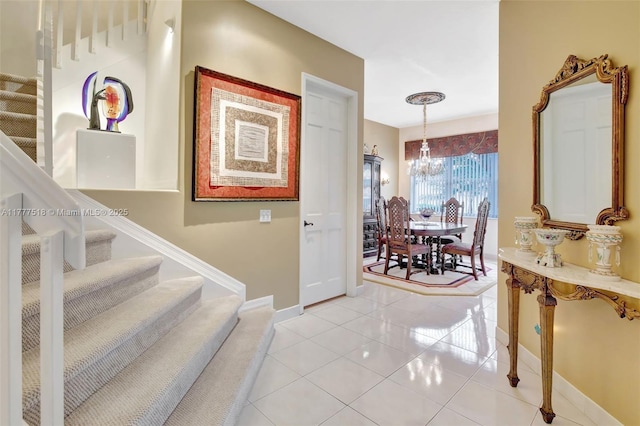 interior space featuring an inviting chandelier, baseboards, light tile patterned floors, and stairway