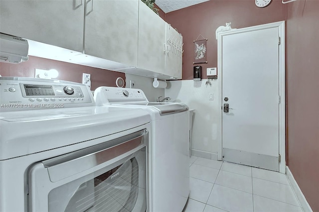 washroom with baseboards, washer and clothes dryer, light tile patterned flooring, and cabinet space