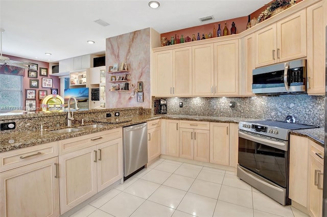 kitchen with light brown cabinetry, stone countertops, a sink, stainless steel appliances, and decorative backsplash