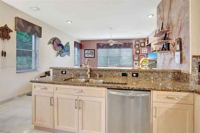 kitchen with dark stone countertops, a ceiling fan, visible vents, stainless steel dishwasher, and a sink