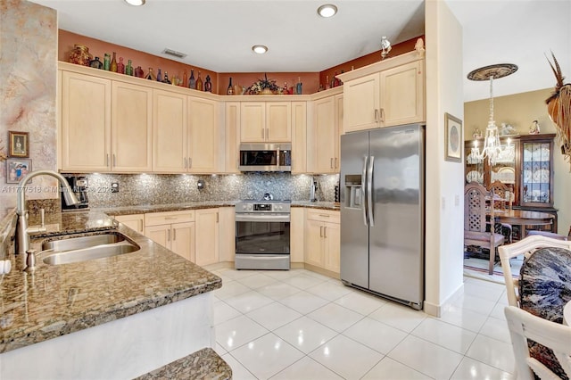 kitchen featuring light stone countertops, visible vents, appliances with stainless steel finishes, a sink, and backsplash