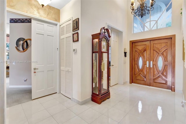 entryway featuring light tile patterned floors, baseboards, and a chandelier