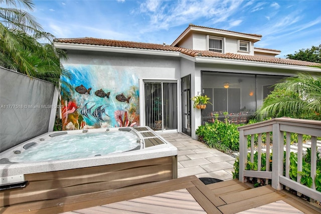 back of property featuring a covered hot tub, stucco siding, and a tile roof