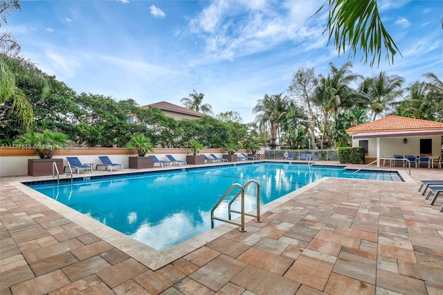 community pool with a patio and fence