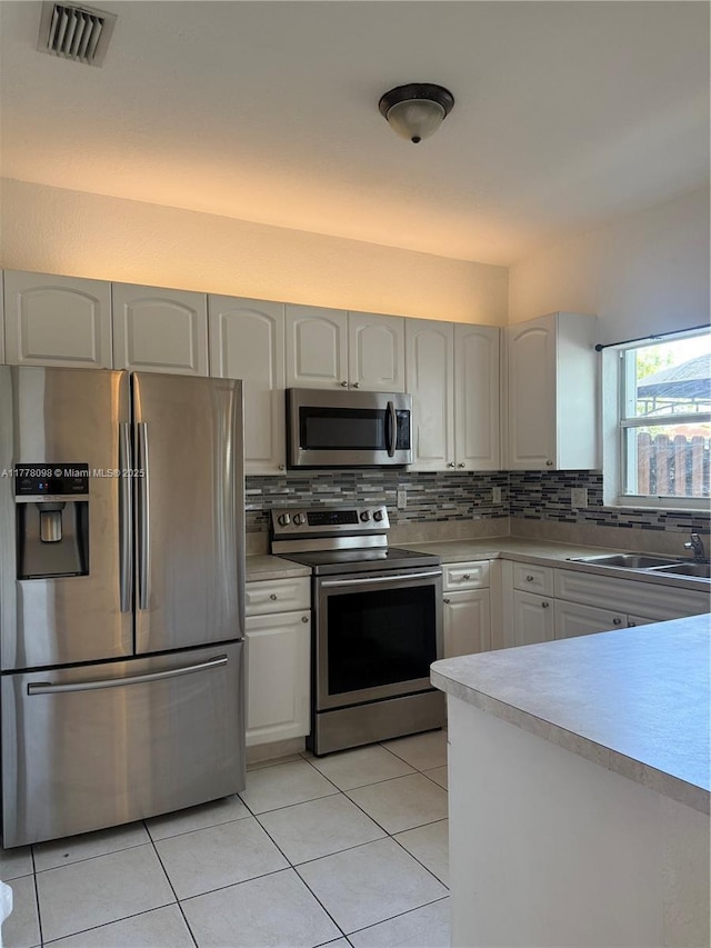 5031 SW 135th Ave Unit 5031, Miramar, FL 33027 - kitchen with appliances with stainless steel finishes, tasteful backsplash, light countertops, light tile patterned floors, and white cabinetry