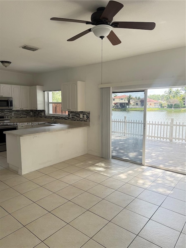 5031 SW 135th Ave Unit 5031, Miramar, FL 33027 - kitchen featuring appliances with stainless steel finishes, backsplash, a peninsula, a ceiling fan, and white cabinetry