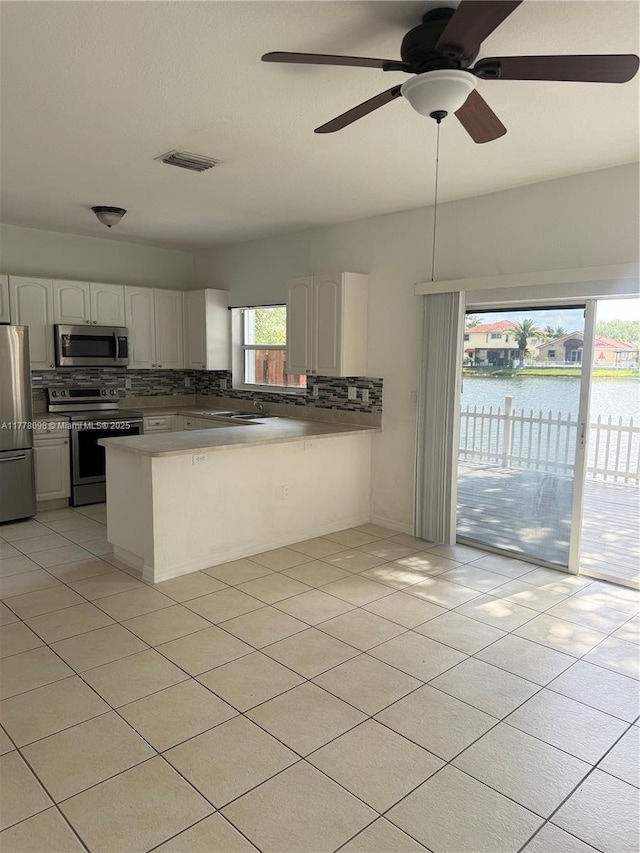 5031 SW 135th Ave Unit 5031, Miramar, FL 33027 - kitchen featuring appliances with stainless steel finishes, decorative backsplash, a peninsula, white cabinets, and a ceiling fan