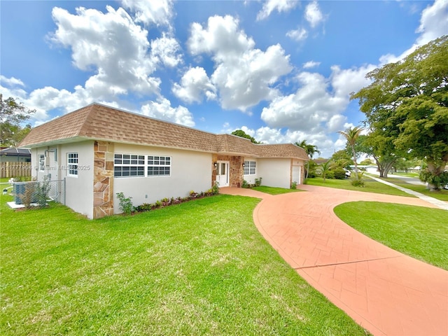 view of front of property with driveway, stucco siding, fence, and a front lawn