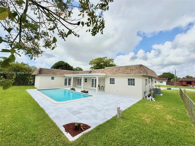 rear view of property featuring cooling unit, a lawn, stucco siding, and a patio