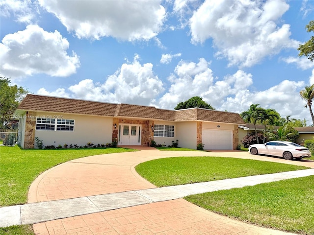 view of front facade featuring a front lawn, stucco siding, an attached garage, and curved driveway