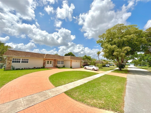 single story home featuring stucco siding, a front yard, curved driveway, and a garage