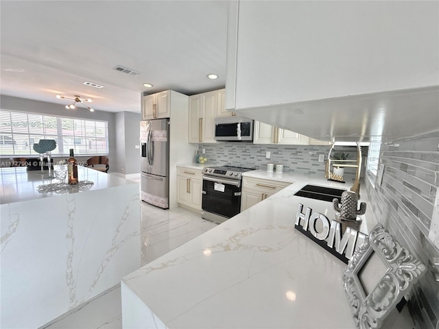 kitchen with decorative backsplash, marble finish floor, light stone countertops, appliances with stainless steel finishes, and a sink