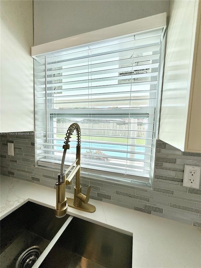 interior details with a sink, tasteful backsplash, and light stone counters
