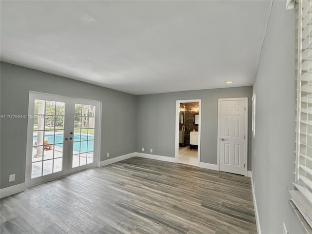 empty room with baseboards, wood finished floors, and french doors