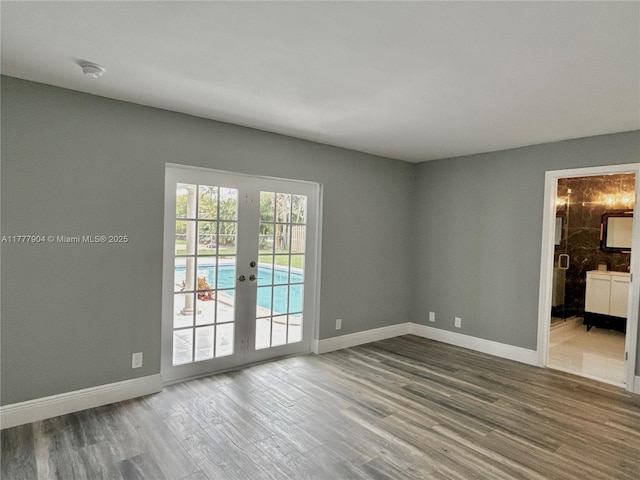 empty room featuring baseboards, wood finished floors, and french doors