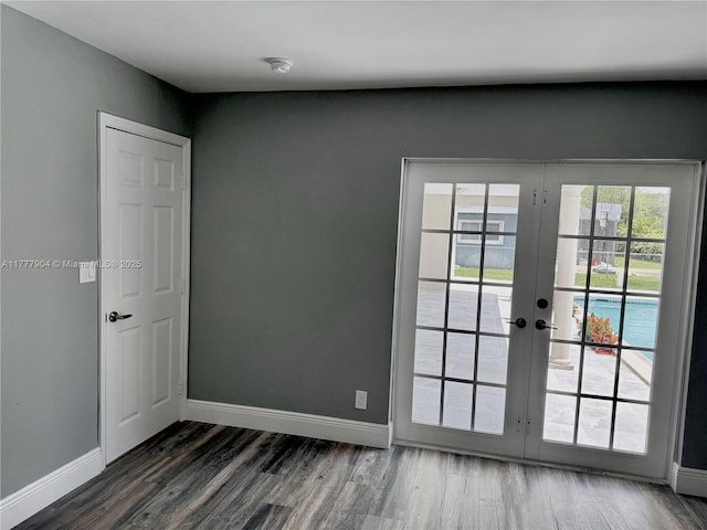 empty room featuring french doors, dark wood-style flooring, and baseboards