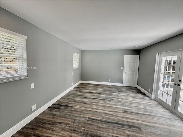 spare room with baseboards, wood finished floors, and a healthy amount of sunlight