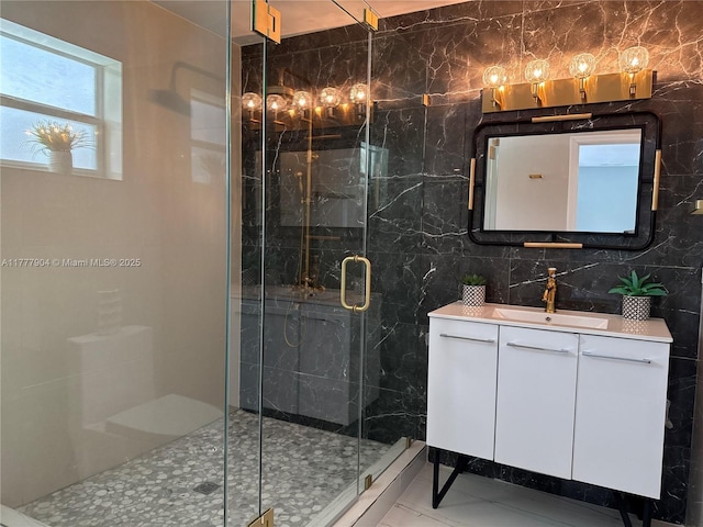 bathroom featuring marble finish floor, vanity, a marble finish shower, and tile walls