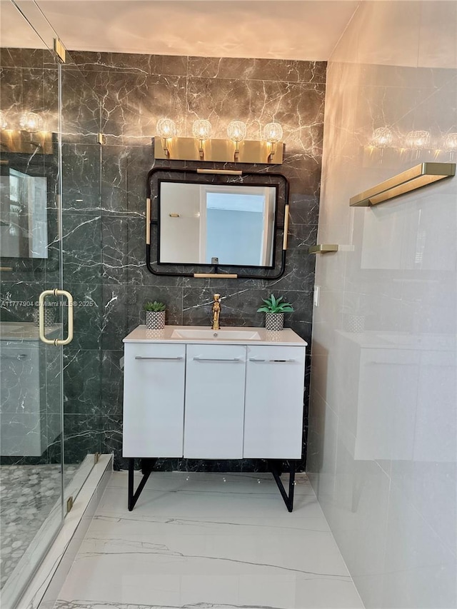 bathroom featuring marble finish floor, vanity, a stall shower, and tile walls