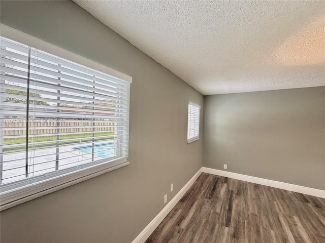 empty room featuring dark wood-style floors, baseboards, and a textured ceiling