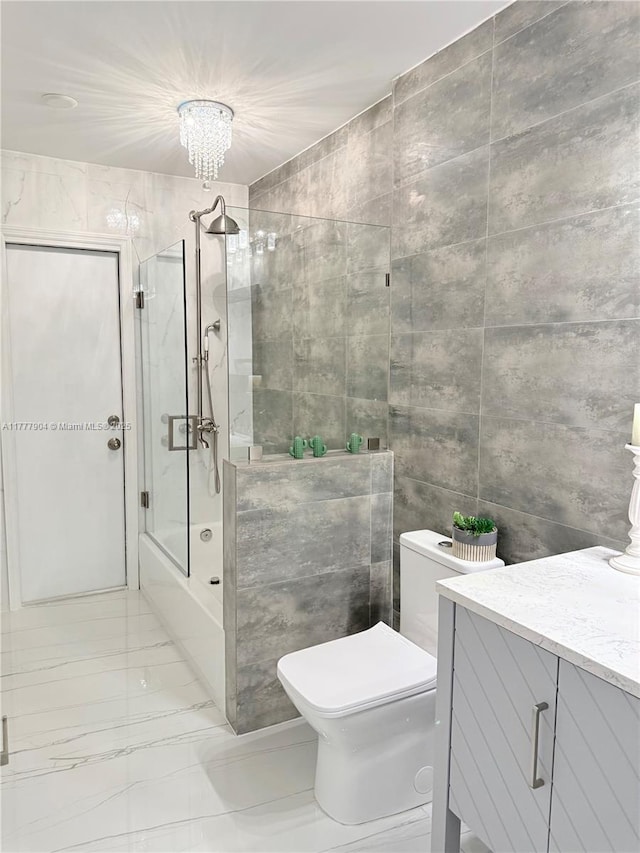full bathroom featuring toilet, vanity, bath / shower combo with glass door, marble finish floor, and tile walls