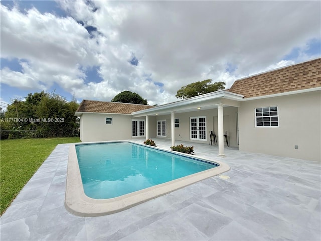 outdoor pool featuring a lawn and a patio