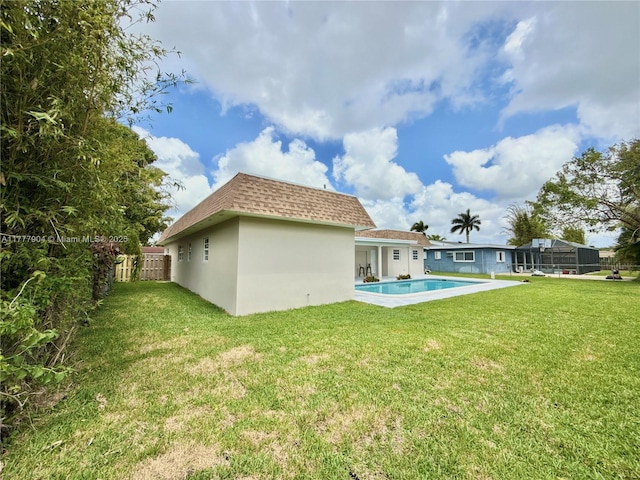 back of property with a lawn, stucco siding, fence, and a shingled roof
