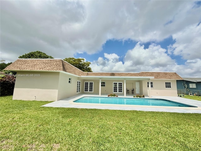 rear view of property with an outdoor pool, a patio, stucco siding, and a lawn