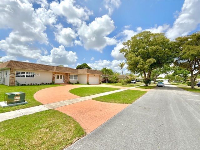 view of front of home featuring a front yard, decorative driveway, an attached garage, and stucco siding
